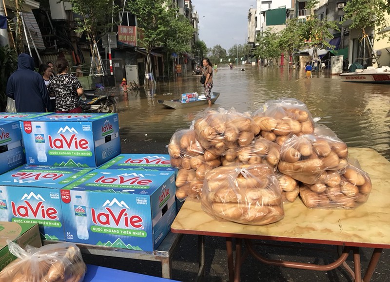 Một số người dân tổ chức phát nước uống, bánh mì miễn phí cho người dân bị lũ chia cắt tại phường Chương Dương