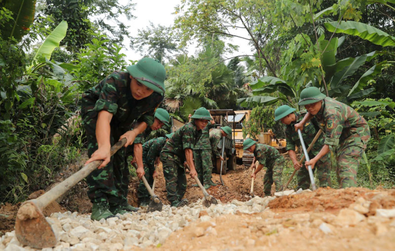 Trời mưa, một số đoạn đường ngập nước, sình lầy, các chiến sĩ phải nạo vét bùn, san lấp đường để giúp xe chở vật liệu di chuyển được lên vị trí móng cột. Ảnh: Thành Trung