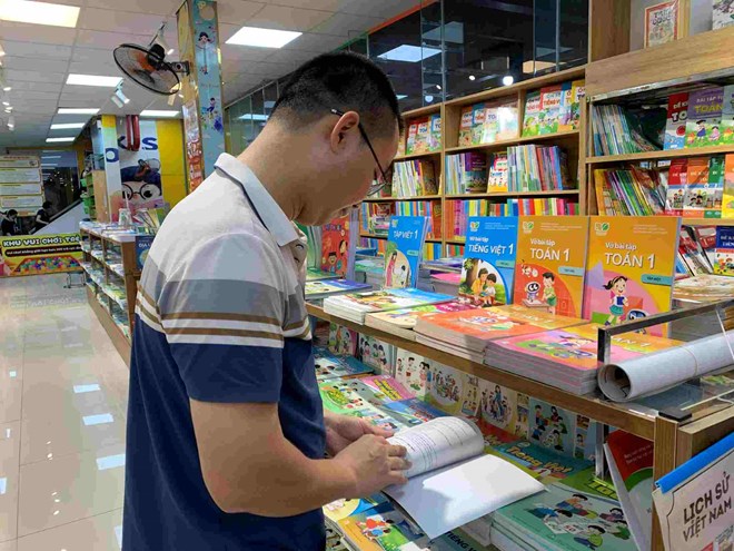Anh Phạm Văn Thắng chọn sách giáo khoa cho con chuẩn bị lên lớp 2. Ảnh: Thanh Hằng