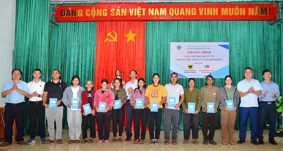 Giám đốc BHXH tỉnh Gia Lai Vũ Mạnh Chữ cùng chính quyền và nhà tài trợ trao thẻ BHYT cho người dân. Ảnh: Thu Hà